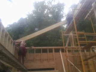 Carpenter raising a rafter beam on a new second story frame in Durant