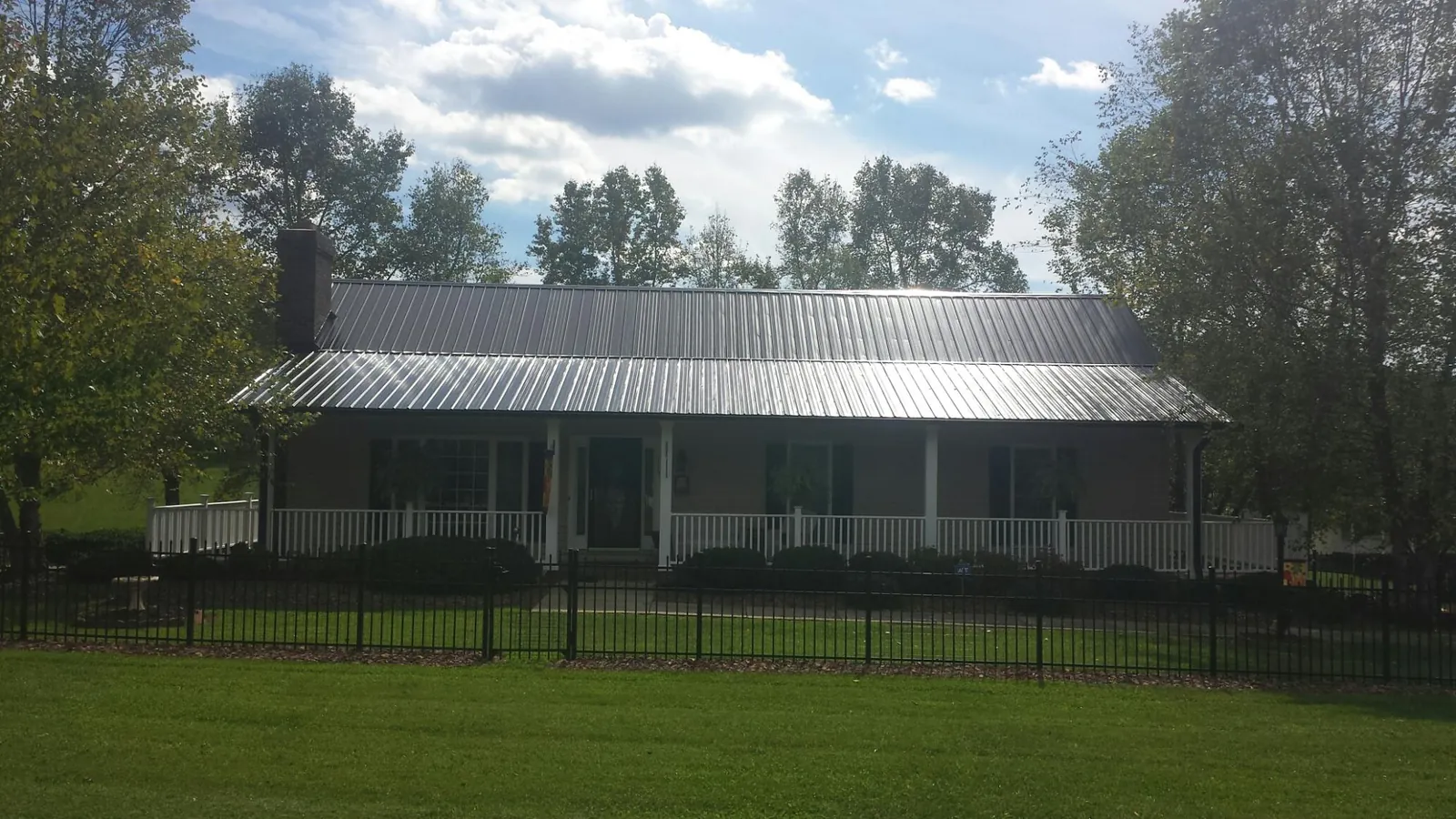 Gray metal roof on a brick ranch with a full width front porch — Gutter Guard Installation work by our crew in Durant